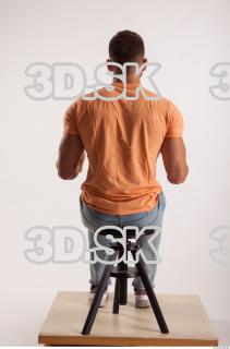 Sitting pose orange thsirt light blue jeans of bodybuilder Harold…